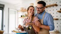 Young happy couple is enjoying and preparing healthy meal in their kitchen together