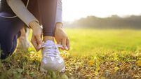 young woman runner tying her shoes preparing for a jog outside at morning
