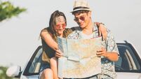 Beautiful young couple holding map outdoors. Road trip summer vacation concept.