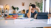 Young teenage boy studying at home using digital tablet while sitting on dining table