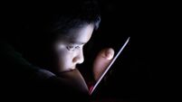 Close up of young kid using smart phone at night