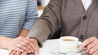 Close Up Of Woman Sharing Cup Of Tea With Elderly Parent
