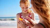 Lovely mother applying sunscreen on cute little girl on cheeks