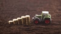 Tractor miniature with coins on fertile soil land