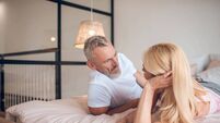 Grey-haired man and a blonde woman lying on the bed and looking at each other