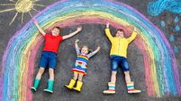 three little children, two school kids boys and toddler girl having fun with with rainbow picture drawing with colorful chalks o