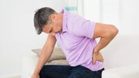 Man Having Backache While Sitting On Sofa