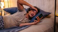 Mid-Adult Man Receiving A Surprising Text Message On His Phone In The Bed At Night