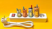 A power strip with five outlets, with four rolled-up 4-euro bills secured by mini clothespins inserted into the space of each so